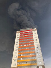 Large fire with black smoke. Burning industrial building, warehouse. A pillar of black smoke in the sky.