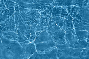 Defocus blurred transparent blue colored clear calm water surface texture with splashes and bubbles. Trendy abstract nature background. Water waves in sunlight with copy space. Blue water shine