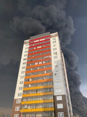Large fire with black smoke. Burning industrial building, warehouse. A pillar of black smoke in the sky.
