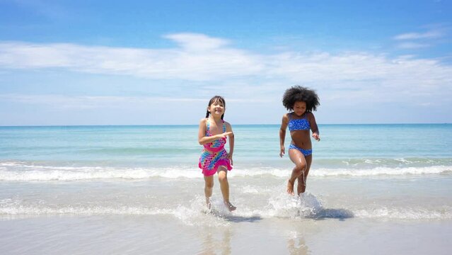 Group of Diversity child girl friends running and playing sea water at tropical beach together on summer vacation. Happy children kids enjoy and fun outdoor lifestyle travel ocean on beach holiday.
