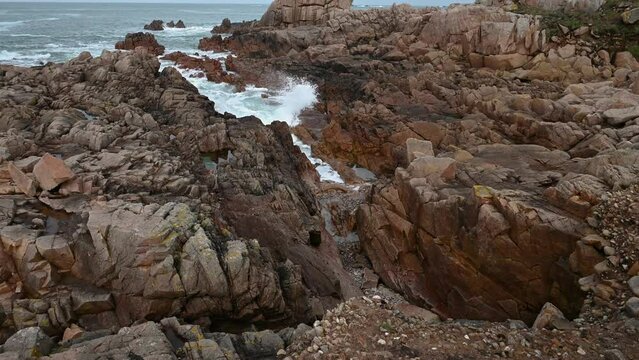 Rocky foreshore with granite boulders and sea flowing into crevice and open sea beyond