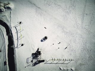 Aerial overhead drone view of school playground equipment covered in snow.