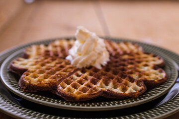 A freshly baked waffle in it decorated with cream on a green plate
