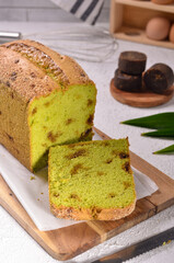 Klepon Pillow Loaf cake made freshed by coconut, brown sugar, green pandan leaves, sugar , eggs and flour,  siolated on white and wooden background 