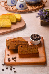 Homemade chocolate sponge cake or chiffon cake on white plate so soft and delicious with ingredients: eggs, flour, milk on wood table. Homemade bakery concept for background and wallpaper.