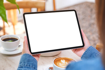 Mockup image of a woman holding digital tablet with blank white desktop screen with cake and coffee...