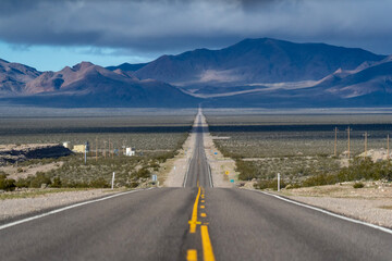 Road to the horizon between mountains and deserts. Beautiful view of way to infinity. Us road and...