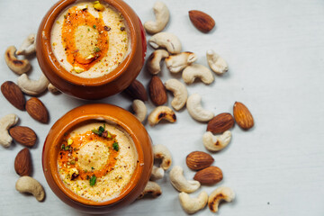 Delicious Kulfi ice cream in two clay pots on a white background with cashews and almonds. - obrazy, fototapety, plakaty
