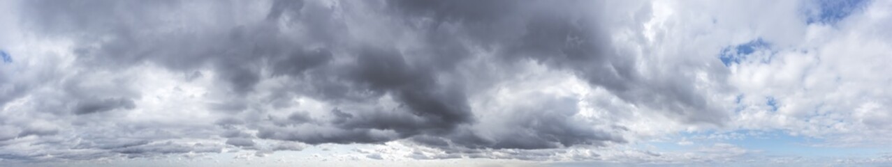 dramatic blue sky with dark gray clouds before rain. wide aerial panorama.