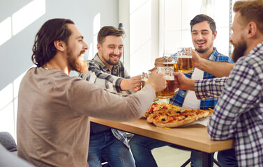 Smiling bearded male best friends with beer and pizza having fun sitting at home and laughing. Portrait of attractive, modern, positive guys enjoying spending time together at the party.