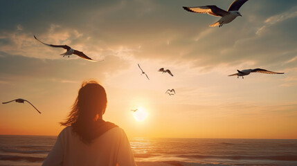 Silhouette of a woman on a beach at sunset looking at birds fly