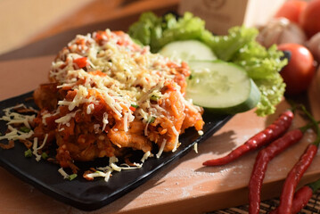 ayam geprek is indonesian spicy fried chicken with chilli sauce. served with vegetable and cheese on toping.
