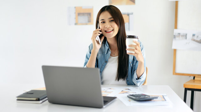 Woman architect drinking coffee and use smartphone to talking wi