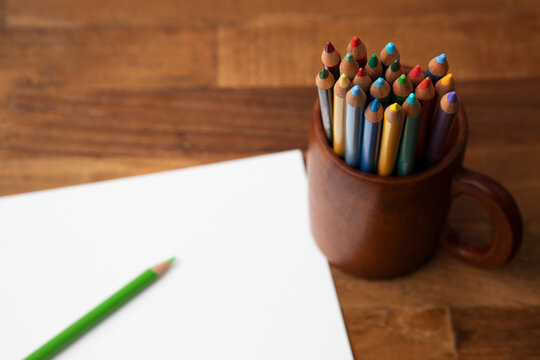 colored pencils in a mug on wooden desk