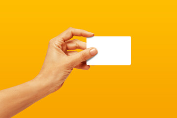 Obraz premium Woman hand showing credit card, or card, or business card or voucher, isolated on orange yellow gradient background, template, mockup