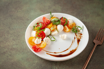 Salad with arugula, mozzarella and tomatoes in a plate on the table. Caprese salad.