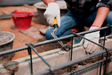 worker installing brick masonry on exterior wall with trowel putty knife