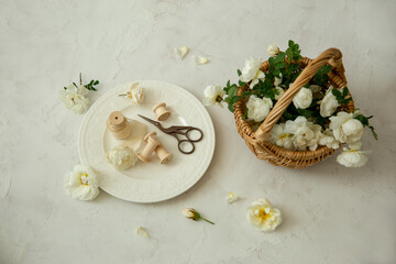 Obraz na płótnie Canvas Scissors, white flowers and a basket of white flowers on a light background