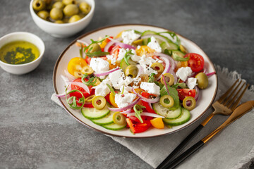 Greek salad of fresh cucumber, tomato, sweet pepper, arugula, red onion, feta cheese and olives with olive oil. Healthy food.