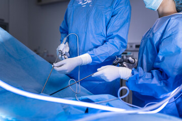 Three surgeons doing laparoscopic surgery. Doctors looking at image on monitor. Medicine and...