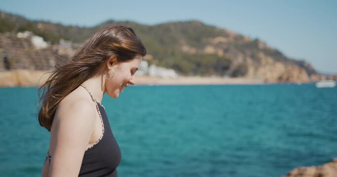 Brown hair girl smiling and looking at the camera in front of the sea