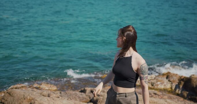 Girl looking at the ocean standing on rocks