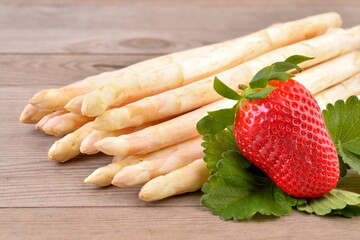 Fresh white asparagus and red strawberry on wooden background.  - 586454891