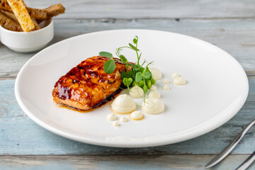 Grilled salmon fillet with sauces next to it on a white porcelain plate