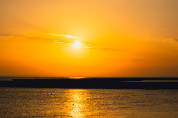 Reflection of sunlight over sea surface at sunset. Orange and gold blue sky. Scenic Gold sea. Dramatic Yellow sun coming out of the sea. Majestic summer landscape