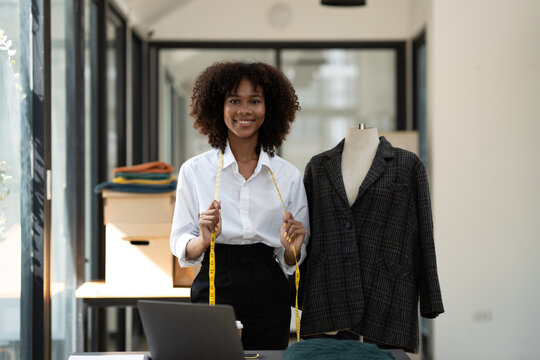 African fashion designer or dressmaker American takes the idea and presents the design of the new collection with fabric samples and laptop sketches. work in the studio.