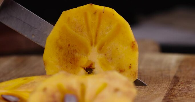 Half-ripe orange persimmon, fresh ripe persimmon cut into pieces on a cutting board with a sharp knife