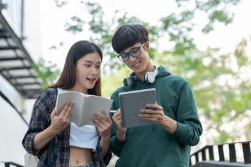 Two Asian students studied and researched together with laptop computers and journaling in an outdoor biological analogy at university.