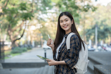 Naklejka premium Young Asian female student standing with a beautiful smile carrying a backpack Confidence in preparation for submitting a biological report at university.
