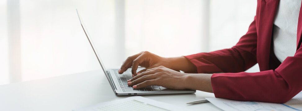 African american businesswoman sitting and recording data details in financial business Online marketing plan to process and send emails for meeting preparation sitting at laptop desk in office. - Powered by Adobe