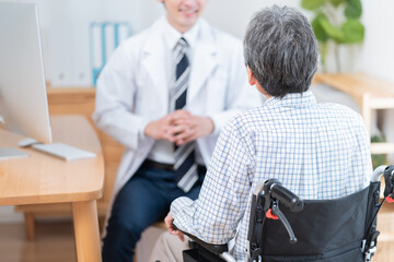医者と話す高齢の患者（車椅子・介護）