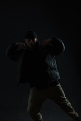 Fashionable professional dancer guy in stylish black clothes is dancing in the dark. Dancing man silhouette