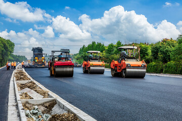 Construction site is laying new asphalt pavement, road construction workers and road construction machinery scene. Highway construction site scene. © ABCDstock