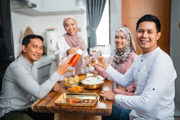 muslim woman serving drink for her friend and family at home having dinner together