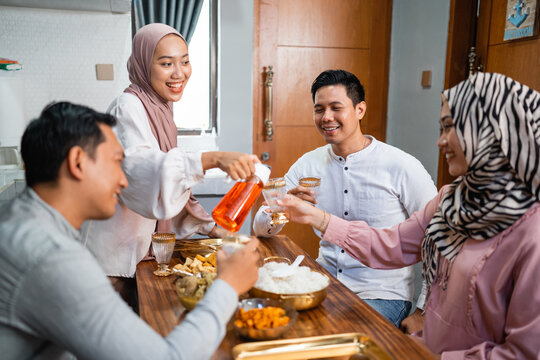 muslim woman serving drink for her friend and family at home having dinner together