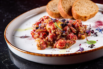 Raw beef meat tartar with sauce in plate