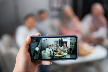 Muslim friends get together while celebrating Idul Fitri taking photo using mobile phone