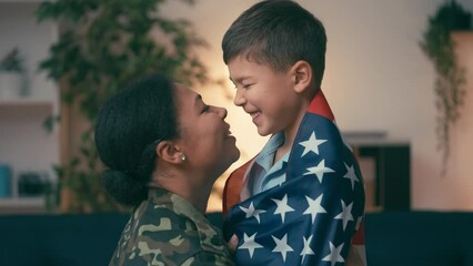 Biracial military mother and son wrapped in US flag nuzzling, patriotic family - Powered by Adobe