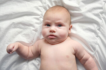 Closeup portrait of Newborn baby on white blanket. Soft focus. Infant is lying, yawning. One, two...