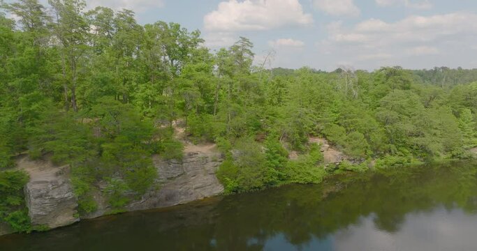 Aerial: Drone View Of Man And Woman Walking Amidst Green Trees On Cliff By River During Vacation - Tuscaloosa, Alabama
