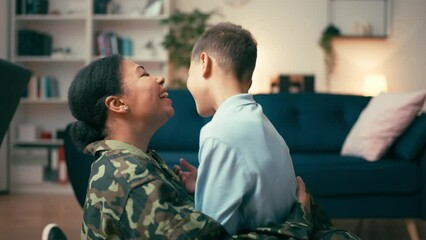 Happy military mother tickling and playing with excited little son home, family