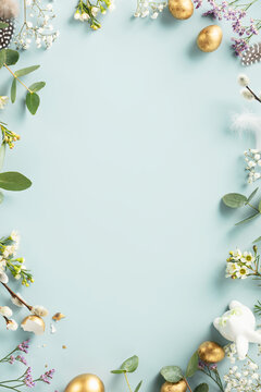 Happy Easter concept with golden easter eggs, feathers and spring flowers. Easter background with copy space. Flat lay