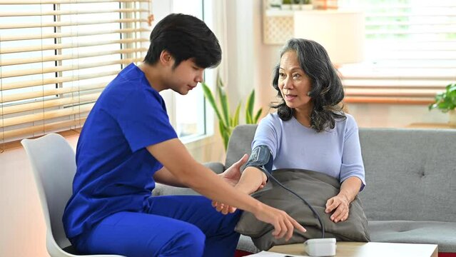 Caregiver measuring arterial blood pressure older patient with sphygmomanometer during a home visit. Seniors hypertension concept