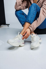 Casual women's fashion. Sports shoes for women. Slender female legs in jeans and white stylish casual sneakers. Women's comfortable summer shoes.