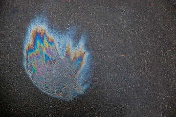 Oil slick looks like a fire on the asphalt road background. Oil stain on Asphalt, color Gasoline...