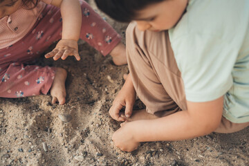 Little kids playing in a sandbox with sand, digging with hands. two children in the yard. Family activity concept. Summer vacation concept.